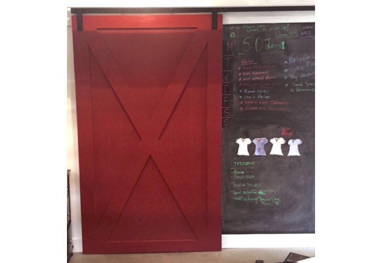 Red sliding barn door with black track next to chalkboard 